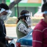 Portando una careta, cubrebocas y guantes, una mujer habla por teléfono en las afueras del Hospital de Infectología en la Ciudad de México