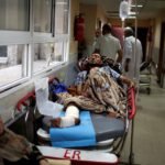 Injured Palestinian lies on a bed in the corridor of a hospital in Gaza City